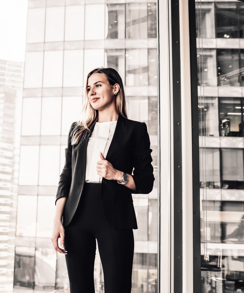 Cheerful blonde female manager in formal outfit enjoying job and Cheerful blonde female manager in formal outfit enjoying job and successful career in business, smiling beautiful woman boss dressed in elegant suit standing near panoramic windows in office